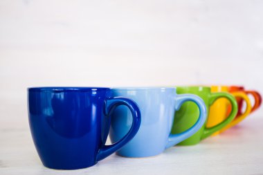 Beyaz ahşap arka plan üzerinde renkli kahve fincanı yığını