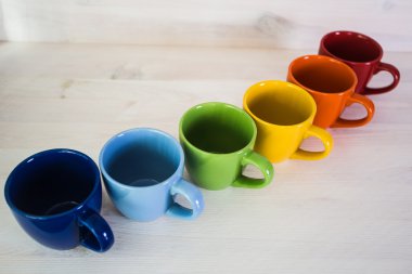 Beyaz ahşap arka plan üzerinde renkli kahve fincanı yığını