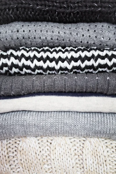 Stack of various woolen sweaters on a white wooden background — Stock Photo, Image
