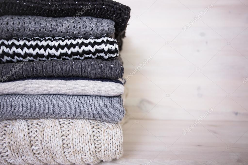 stack of various woolen sweaters on a white wooden background