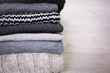 Beyaz ahşap zemin üzerinde çeşitli yün kazak yığını