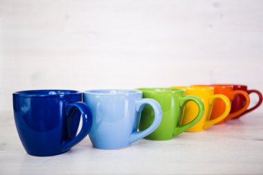 Beyaz ahşap arka plan üzerinde renkli kahve fincanı yığını