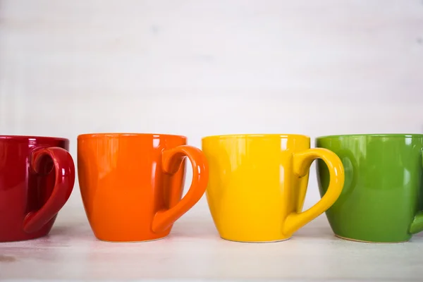 Pile de tasses à café colorées sur un fond en bois blanc — Photo