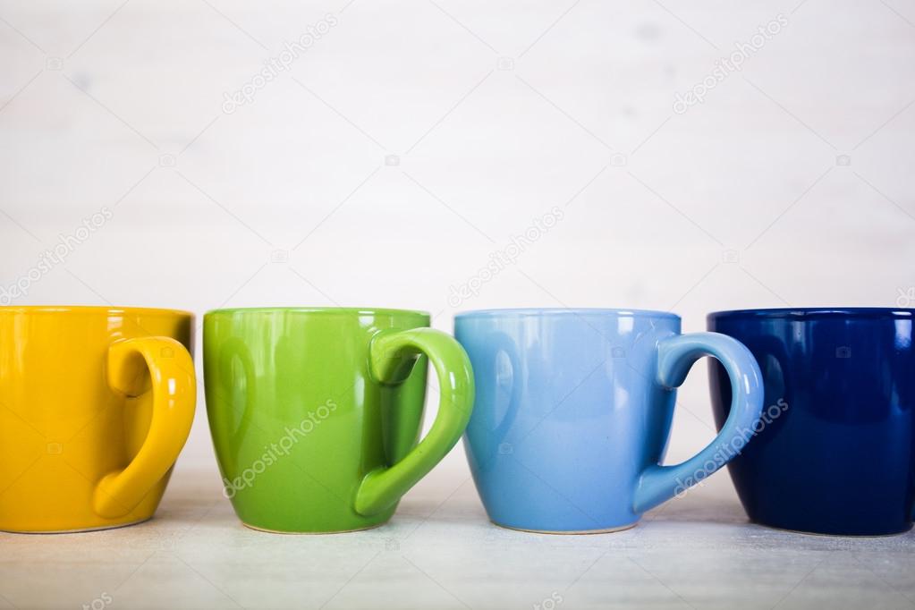 stack of colorful coffee cups on a white wooden background