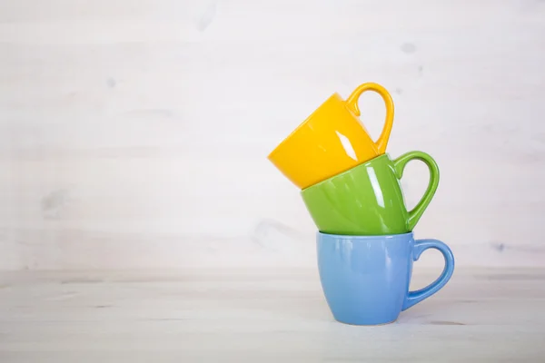 Pile de tasses à café colorées sur un fond en bois blanc — Photo