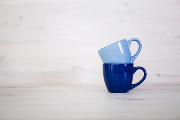 Pila di tazze di caffè colorate su uno sfondo di legno bianco — Foto Stock