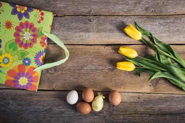Lale ve yumurta ile hediye çanta ahşap arka plan üzerinde. Paskalya arka