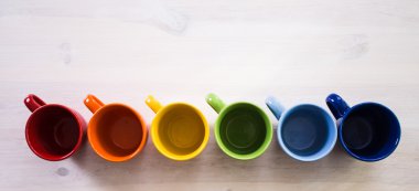 Beyaz ahşap arka plan üzerinde renkli kahve fincanı yığını