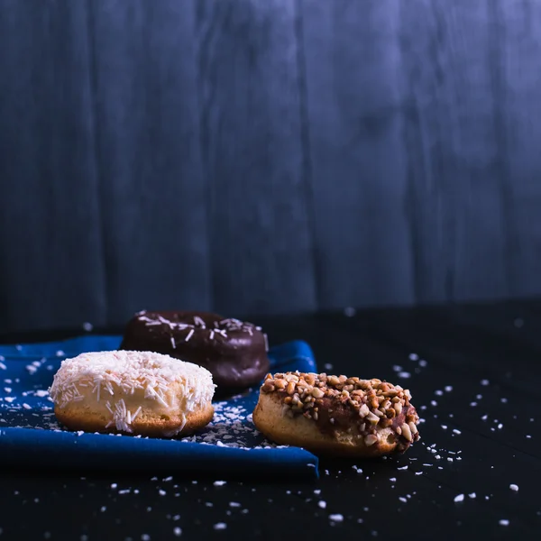 Rosquillas con polvo diferente sobre un fondo de madera negro — Foto de Stock