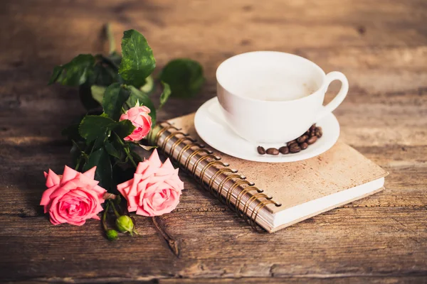 Cup of coffee with milk and pink roses and books on the old wooden background — Stock Photo, Image