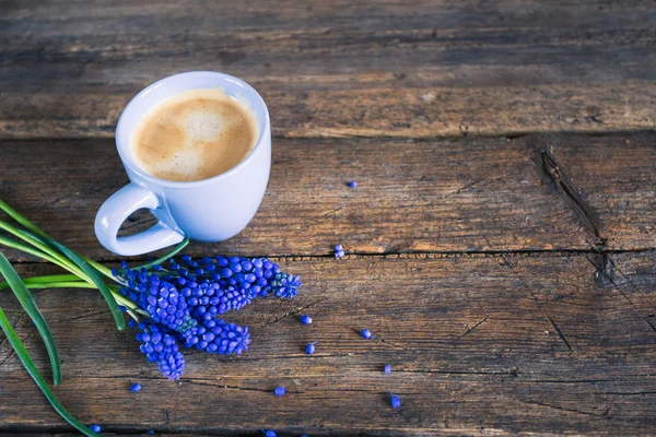 Niebieskie kwiaty i filiżankę kawy na tle drewniane — Zdjęcie stockowe