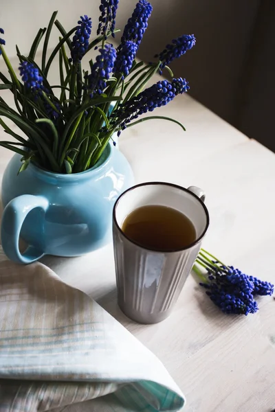 Blå blommor i en tekanna med en kopp te på trä bakgrund. — Stockfoto