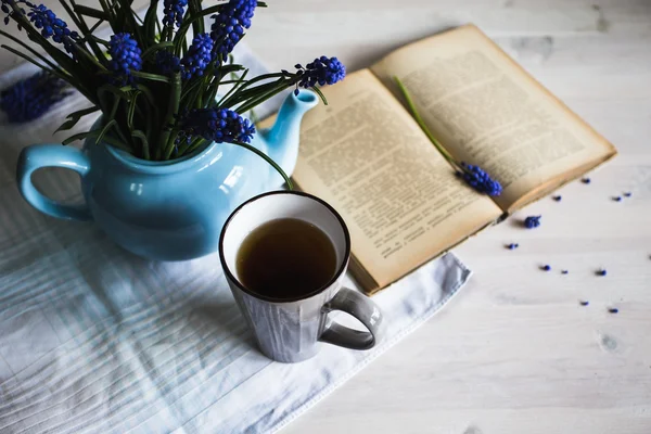 Cup of tea with blue flowers and a book on wooden background. Vintage — Stock Photo, Image