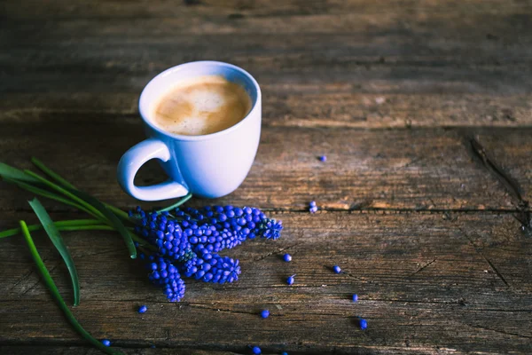 Синие цветы и чашка кофе на деревянном фоне — стоковое фото