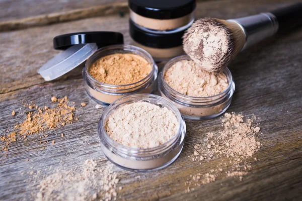 ahşap arka plan üzerinde makyaj için fırça ile farklı renkteki mineral toz