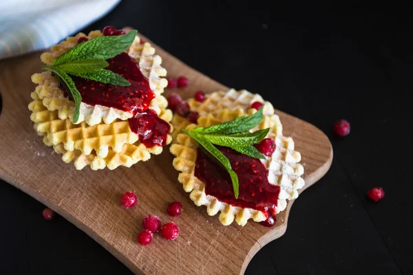 Waffle com geléia de baga, açúcar em pó e hortelã sobre fundo preto — Fotografia de Stock