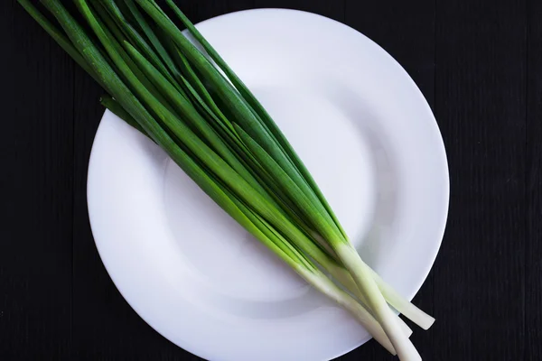 Grüne Zwiebeln auf schwarzem Hintergrund — Stockfoto