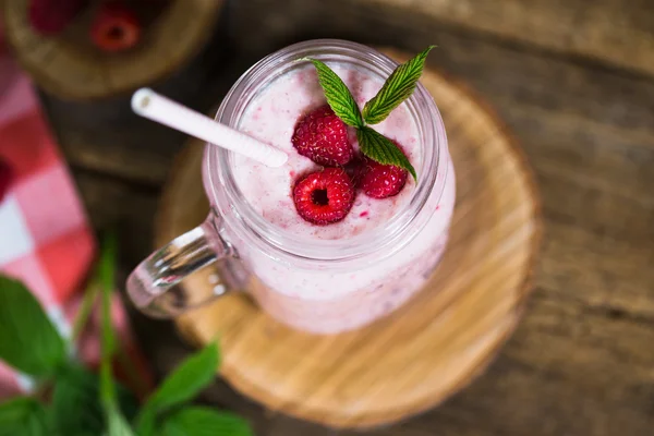 Batido de frambuesa rosa en un frasco de albañil con pajitas sobre un fondo de madera rústica —  Fotos de Stock