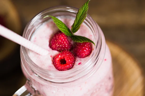 Batido de frambuesa rosa en un frasco de albañil con pajitas sobre un fondo de madera rústica —  Fotos de Stock