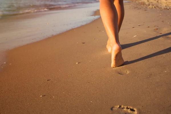 Donna che cammina sulla spiaggia al tramonto Immagine Stock
