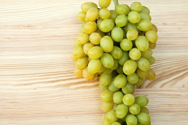 Ramo de uvas maduras sobre un fondo de madera — Foto de Stock