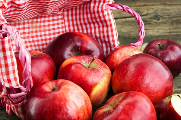 Ahşap zemin üzerinde bir sepet içinde kırmızı elmalar — Stok fotoğraf