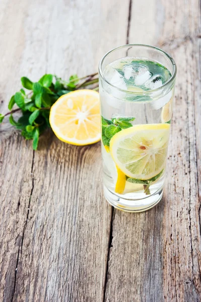 Lemonade with fresh lemon and mint in glass on wooden background — Stock Photo, Image