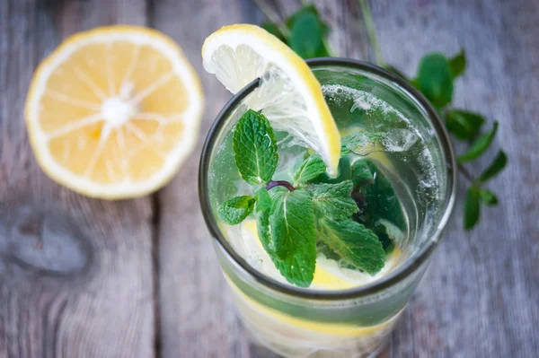 Лимонад со свежим лимоном и мятой в стекле на деревянном фоне — стоковое фото
