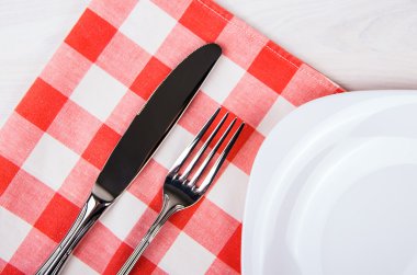 Boş tabak, bıçak ve çatal ve ahşap masa üzerinde kırmızı peçete