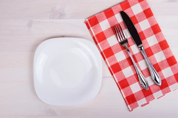 Порожня тарілка, ніж і виделка і червона серветка на дерев'яному столі — стокове фото