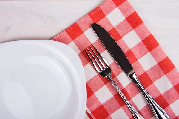 Prato vazio, faca e garfo e guardanapo vermelho na mesa de madeira — Fotografia de Stock