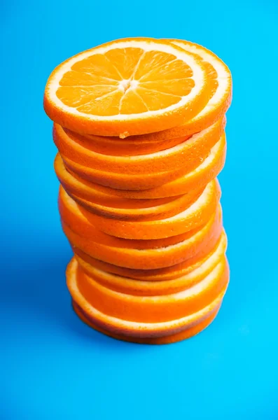 Стопка нарезанных апельсинов на синем фоне — стоковое фото