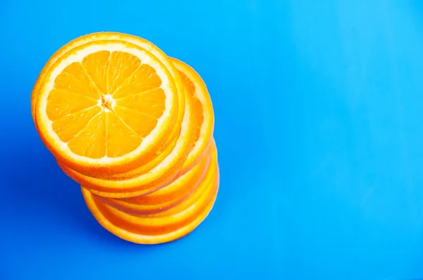 Pilha de laranjas fatiadas em um fundo azul — Fotografia de Stock