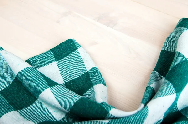 Green folded tablecloth over bleached wooden table — Stock Photo, Image