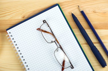 açık defter kalem ve bir masa üzerine gözlük ile giderleri