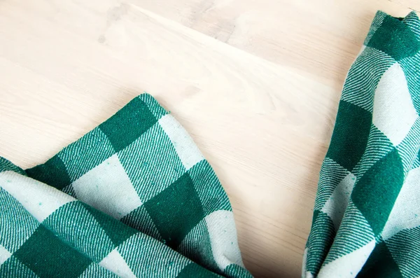 Green folded tablecloth over bleached wooden table — Stock Photo, Image