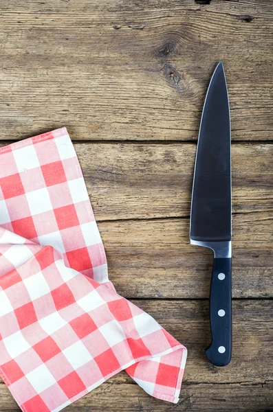 Cutting breadboard and knife over red grunge gingham tablecloth background — Stock Photo, Image