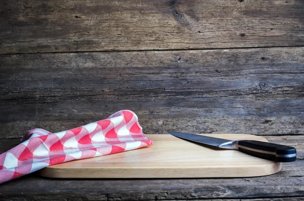 Planche à découper vide avec un couteau et une serviette tranchants sur une table en bois grunge en détresse — Photo