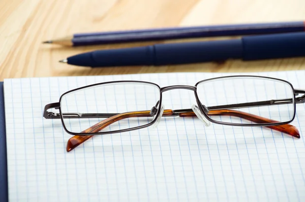 Overhead van notitieblok openen met pen en bril op een bureau — Stockfoto