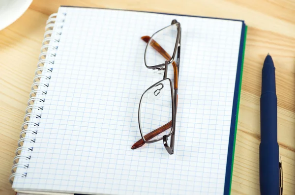 Overhead van notitieblok openen met pen en bril op een bureau — Stockfoto