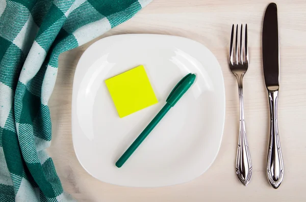 Порожня тарілка, ніж і виделка і зелена серветка на дерев'яному столі — стокове фото