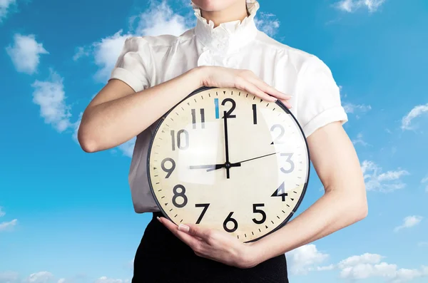 Business woman holding a clock on the sky backround — Stock Photo, Image