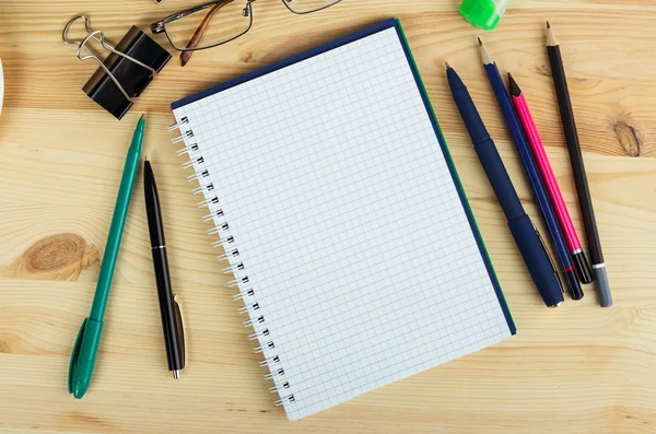 Sobrecarga de cuaderno abierto con bolígrafo y gafas en un escritorio — Foto de Stock