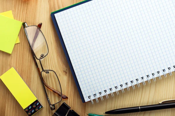 Sobrecarga de cuaderno abierto con bolígrafo y gafas en un escritorio — Foto de Stock