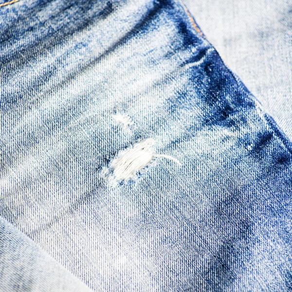 Синя текстура джинсу з отвором і нитками, що показують — стокове фото