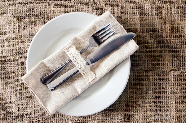 Lege schotel, mes en vork op een servet van jute — Stockfoto