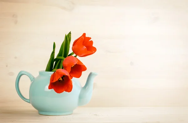 Spring tulips bouquet in teapot over wooden background — Stockfoto