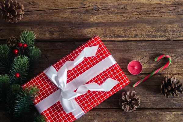 Regalos de Navidad sobre fondo de madera con bastón de caramelo, ramas de abeto, vela, conos . —  Fotos de Stock