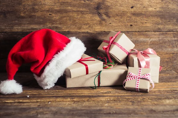 Tarjetas de Navidad y regalos con sombreros de Santa sobre fondo de madera —  Fotos de Stock