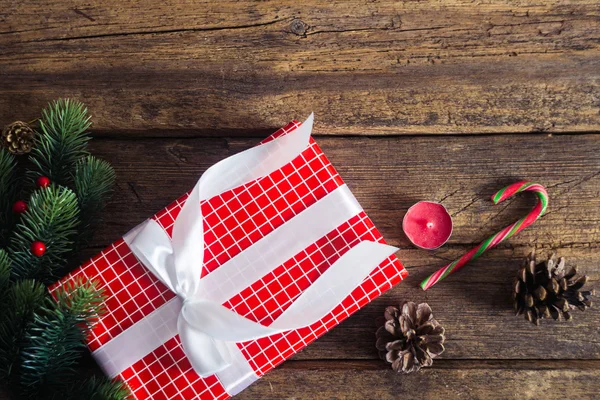 Regalos de Navidad sobre fondo de madera con bastón de caramelo, ramas de abeto, vela, conos . — Foto de Stock